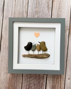 three birds sitting on top of a wooden branch in a shadow box with a heart