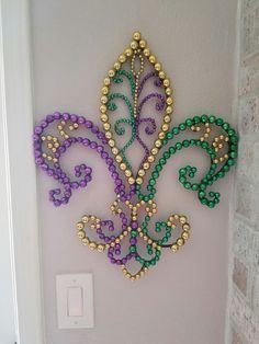 a decorative wall hanging on the side of a white brick wall with beads and pearls