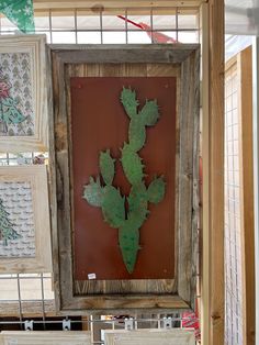 a wooden frame with metal cactus artwork hanging on it's side in a store