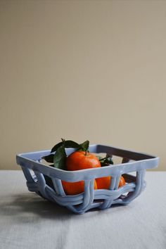 two oranges in a blue basket on a table