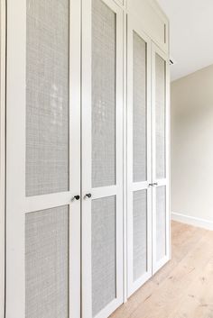 an empty room with white closets and wood flooring on one side, two doors to the other