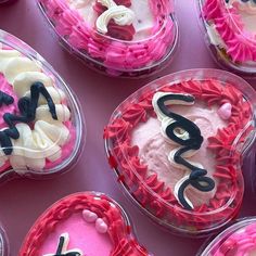 many cupcakes are decorated with icing and pink frosting in the shape of letters