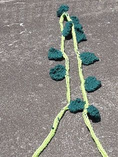 there is a green string attached to the ground with two leaves on it and one leaf has been crocheted