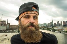 a man with a beard and bandana on standing in front of a cityscape