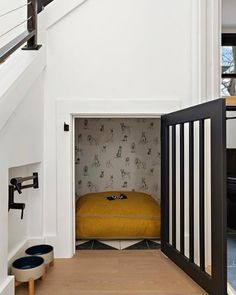 an open door leading to a bed in a room with white walls and wooden floors