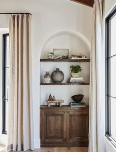 a living room with wooden floors and shelves filled with vases on top of them