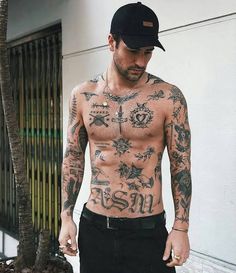 a man with tattoos on his chest walking down the street