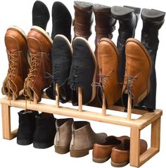 several pairs of shoes are lined up on a wooden shoe rack with two legs and four boots