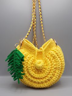 a crocheted yellow purse with green tassels hanging from it's side