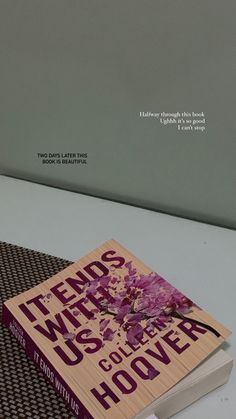 two books sitting next to each other on top of a white table with purple flowers