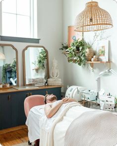 a woman laying on top of a bed next to a table with a mirror above it