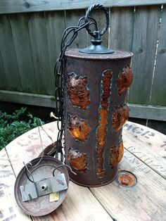 a rusted metal lantern sitting on top of a wooden table next to a fence