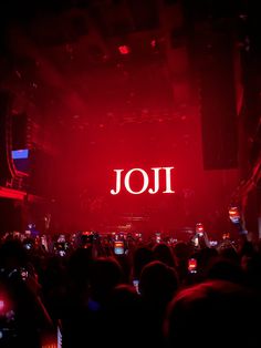 a large group of people in a dark room with red lighting and the word joi on it