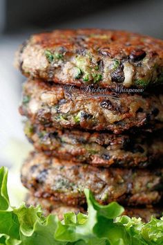 a stack of food sitting on top of a white plate next to lettuce