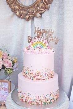 a pink birthday cake sitting on top of a table