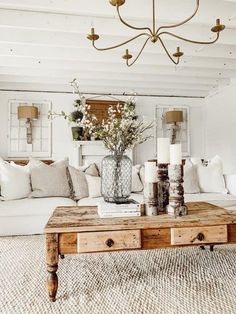 a living room with white couches and wooden coffee table in the center, surrounded by potted plants