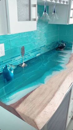 a kitchen counter with blue glass tiles on the backsplash and under running water