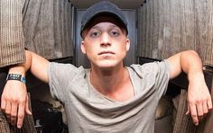 a young man wearing a baseball cap is sitting in the back of an airplane with his hands on his hips