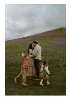 two adults and three children walking in a field with lavenders on the hill behind them