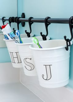 three buckets with toothbrushes hanging from them