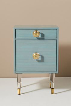 a blue and gold nightstand with two drawers on each side, in front of a beige wall