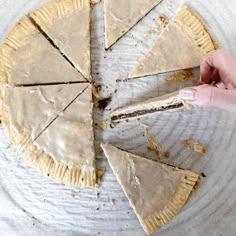 a person holding a piece of pie on top of a white plate with one slice missing