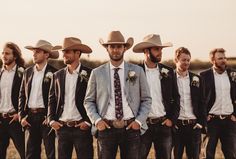 a group of men standing next to each other wearing suits and ties with hats on