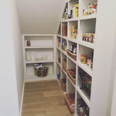 a pantry with shelves filled with food and other items on the floor in an attic