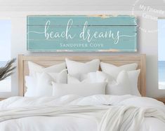 a bed with white sheets and pillows in front of a wooden sign that says beach dreams sandpipe cove