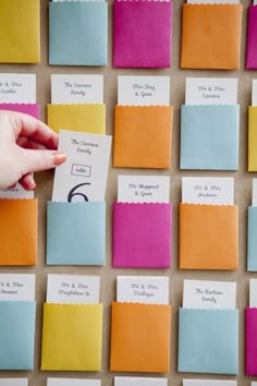 someone is placing post it notes on the bulletin board with colorful sticky notes attached to them