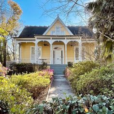 a yellow house with white trim on the front porch and steps leading up to it