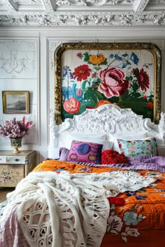 a bed with an ornate headboard and colorful blankets on it's sides in a bedroom