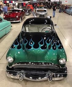 an old car with flames painted on it's hood in a showroom next to other classic cars