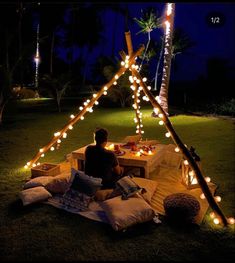 a man sitting in front of a tent with lights on it