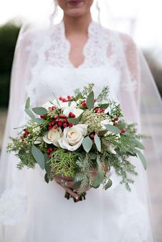 a bride holding a bouquet of flowers and greenery