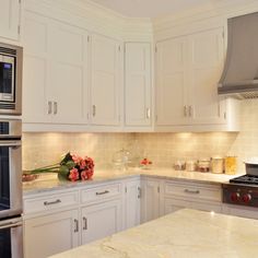 a kitchen with white cabinets and marble counter tops, stainless steel appliances and an oven