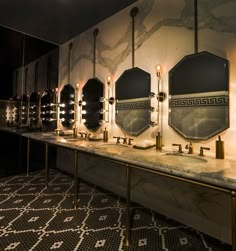 a row of sinks sitting next to each other on top of a tiled floor covered in mirrors