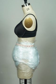 a mannequin wearing a black top and white skirt with a gold circle on it