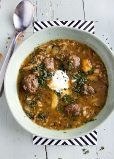 a bowl of soup with meatballs and sour cream in it on a striped place mat