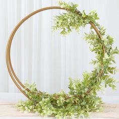 a round wooden frame with green leaves and branches on it, sitting on a table