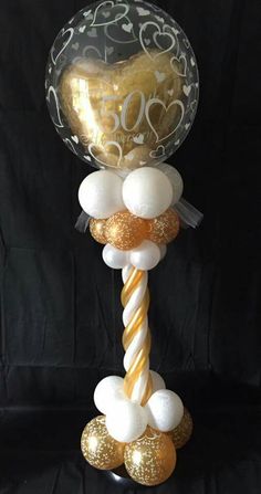 a balloon with gold and white balloons attached to it's side on a black background