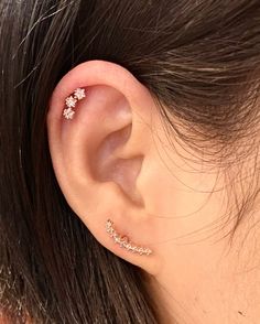 a close up of a person's ear with an ear cuff in the shape of flowers