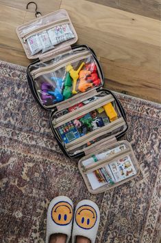 an open suitcase sitting on top of a rug next to someone's feet and shoes