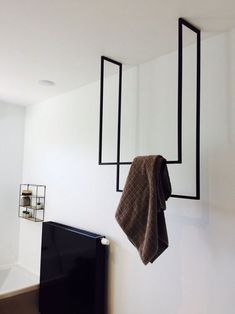 a towel hanging on the wall next to a black cabinet with two mirrors above it