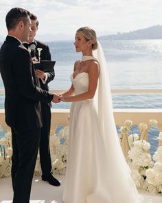 a bride and groom standing next to each other in front of an ocean view ceremony