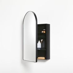 a mirror mounted to the side of a wall next to a shelf with bottles on it