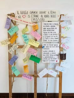 a bulletin board with notes attached to it in front of a wall that has writing on it