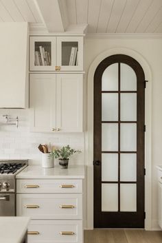 a white kitchen with an arched glass door