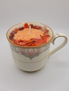 a cup filled with soup sitting on top of a white table next to a candle