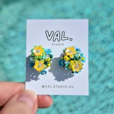 a pair of yellow and blue flower studs on a card with water in the background